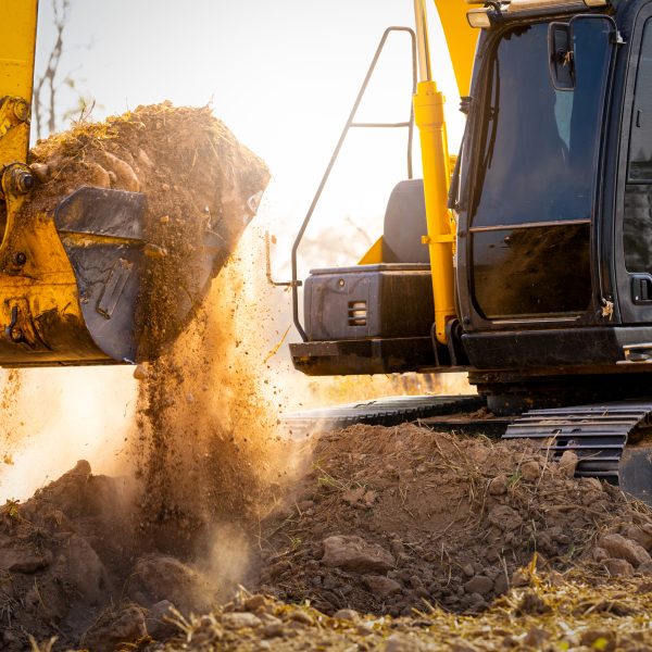 Close-up of excavator at construction site. Backhoe digging soil for earthwork and construction business. Excavating machine at work. Heavy machinery for earth moving and construction site development