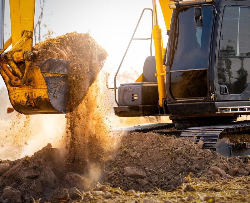 Close-up of excavator at construction site. Backhoe digging soil for earthwork and construction business. Excavating machine at work. Heavy machinery for earth moving and construction site development